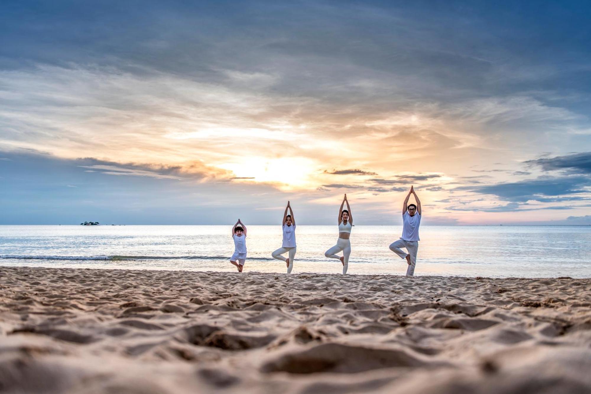 Vinpearl Resort & Spa Phu Quoc Exteriör bild Family practicing yoga on the beach
